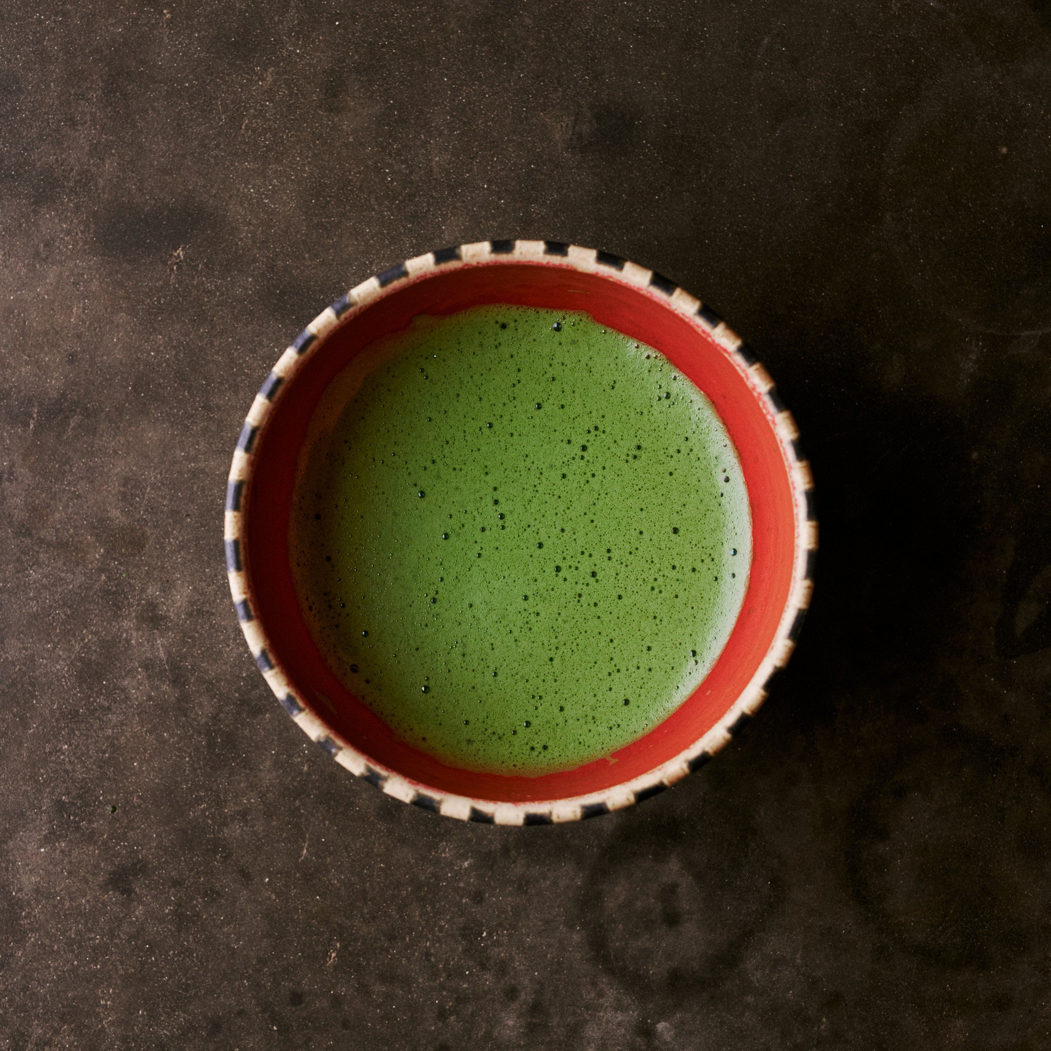 Matcha green tea in HIRAGOUSHI bowl - top view showing vibrant red glaze and geometric pattern